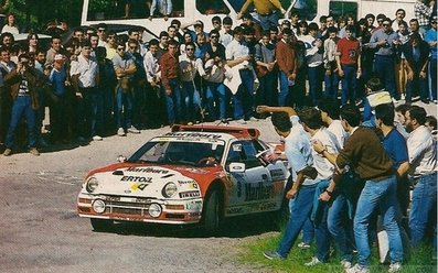 Antonio Zanini Sans - Josep Autet
10° Rally Villa de Llanes 1986. Ford RS 200 (2M 5557 P).

Después de ir todo el rally peleando con Sainz (Renault 5 Maxiturbo / VA-4650-M) por la victoria, cuando quedaban dos tramos para el final y con la segunda plaza asegurada, apareció la lluvia en el tramo del Fito... Todos montaron ruedas de seco.

En la bajada del tramo se sale de la carretera Carlos Sainz, apareciendo poco después Antonio Zanini, que también se sale en la misma curva golpeando el Maxiturbo de Carlos.
Salvador Servià (Lancia Rally 037 / 2M 5511 P) consigue pasar por los pelos y por las indicaciones de Carlos Sainz para que aminorara la velocidad. Después de más de cuatro minutos, Antonio Zanini logra devolver el Ford, (que estaba apoyado al Maxiturbo de Carlos), a la carretera y continuar en carrera, quedando en 4ª posición final del Rally.

El 1 de Junio, Llanes, Asturias, España.
Superficie: asfalto.

Tomaron la salida 52 equipos, finalizaron 35.
@

Palabras clave: Antonio_Zanini;Josep_Autet;Ford;RS200;Villa_Llanes;1986;grupo_B