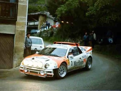 Antonio Zanini Sans - Josep Autet
10° Rally Villa de Llanes 1986. Ford RS 200 (2M 5557 P).

Después de ir todo el rally peleando con Sainz (Renault 5 Maxiturbo / VA-4650-M) por la victoria, cuando quedaban dos tramos para el final y con la segunda plaza asegurada, apareció la lluvia en el tramo del Fito... Todos montaron ruedas de seco.

En la bajada del tramo se sale de la carretera Carlos Sainz, apareciendo poco después Antonio Zanini, que también se sale en la misma curva golpeando el Maxiturbo de Carlos.
Salvador Servià (Lancia Rally 037 / 2M 5511 P) consigue pasar por los pelos y por las indicaciones de Carlos Sainz para que aminorara la velocidad. Después de más de cuatro minutos, Antonio Zanini logra devolver el Ford, (que estaba apoyado al Maxiturbo de Carlos), a la carretera y continuar en carrera, quedando en 4ª posición final del Rally.

El 1 de Junio, Llanes, Asturias, España.
Superficie: asfalto.

Tomaron la salida 52 equipos, finalizaron 35.
@
Palabras clave: Antonio_Zanini;Josep_Autet;Ford;RS;Villa_Llanes;1986;grupo_B