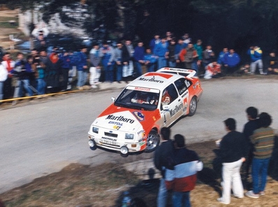Carlos Sainz Cenamor - Antonio Boto
35º Rally Costa Brava 1987. Ford Sierra RS Cosworth (V-7853-BX). Abandonó por la rotura de la transmisión.

Polémica en torno a Sainz
Corrió cómo un reguero de pólvora la voz de que Sainz había sufrido un incidente con dos coches que venían de cara en pleno tramo, un vehículo de la Guardia Civil y otro de la organización, colisionando con uno de ellos.

Carmelo Ezpeleta, director del equipo Race-Marlboro, pedía la anulación del tramo y aseguraba que todo estaba muy claro, filmado desde el helicóptero que permanentemente seguía a Carlos Sainz para obtener tomas televisivas. Pasados los primeros instantes, la versión fue suavizándose, y aunque la organización, en este caso Juan Pons director de carrera, afirmaba que ambos coches estaban parados, Carmelo Ezpeleta aseguró que le habían admitido que bajaban en sentido contrario. lnsinuando una posible reclamación para anular el tramo justo en el momento en el que se supo que Carlos abandonaba definitvamente.

Carlos Sainz realizó una rueda de prensa, alabando la organización y lamentando este punto negro, más que nada porque representaba un grave peligro innecesario, asegurando que rompió la transmisión quizá por el golpe que había dado en la cuneta.

Curiosamente cuando llegó el helicóptero y descendió el cámara de vídeo, se le preguntó sobre el incidente sobre la filmación.
¿Qué incidente? Yo no he visto nada y no he podido filmar nada de esto porque no lo hemos visto. Es más, en el helicóptero nadie ha comentado nada sobre el tema, afirmó “Cherna” González, de Telesport, un cámara que seguía todos los rallyes del Mundial y los mejores de España.

Del 19 al 21 de Febrero.
Al año siguiente la prueba se fusionó con el Rally Catalunya pasando a llamarse Rally Catalunya-Costa Brava, por lo que la edición de 1988 se celebró bajo este nombre.

El Rally tenia un total de 1.139,5 Km con 27 tramos especiales.

Tomaron la salida 106 equipos, finalizaron 51.
@
Palabras clave: ;Ford;Sierra;Cosworth;Costa_Brava;1987
