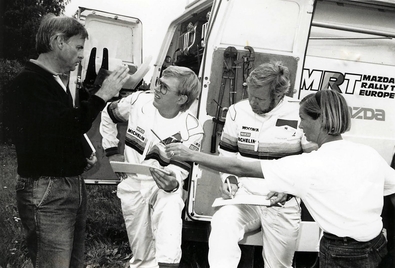 38º 1000 Lakes Rally 1988
Timo Salonen hablando con Achim Warmbold.

También podemos ver a Michèle Espinos-Petit (Biche), (dándole lo que parece un lápiz a Warmbold) y a Seppo Harjanne, copiloto de Timo, a su lado.

Compitieron con Mazda 323 4WD, quedando clasificados en 4ª posición.

Del 26 al 28 de Agosto, Jyväskylä, Finlandia.
Superficie: tierra.

El Rally tenia un total de 1445.95 km de los que 496.32 km divididos en 39 tramos, eran especiales.

Se inscribieron 200 equipos, tomaron la salida 195, finalizaron 84.
@
Palabras clave: Timo_Salonen;Mazda;4WD;Finlandia;1988;Personajes